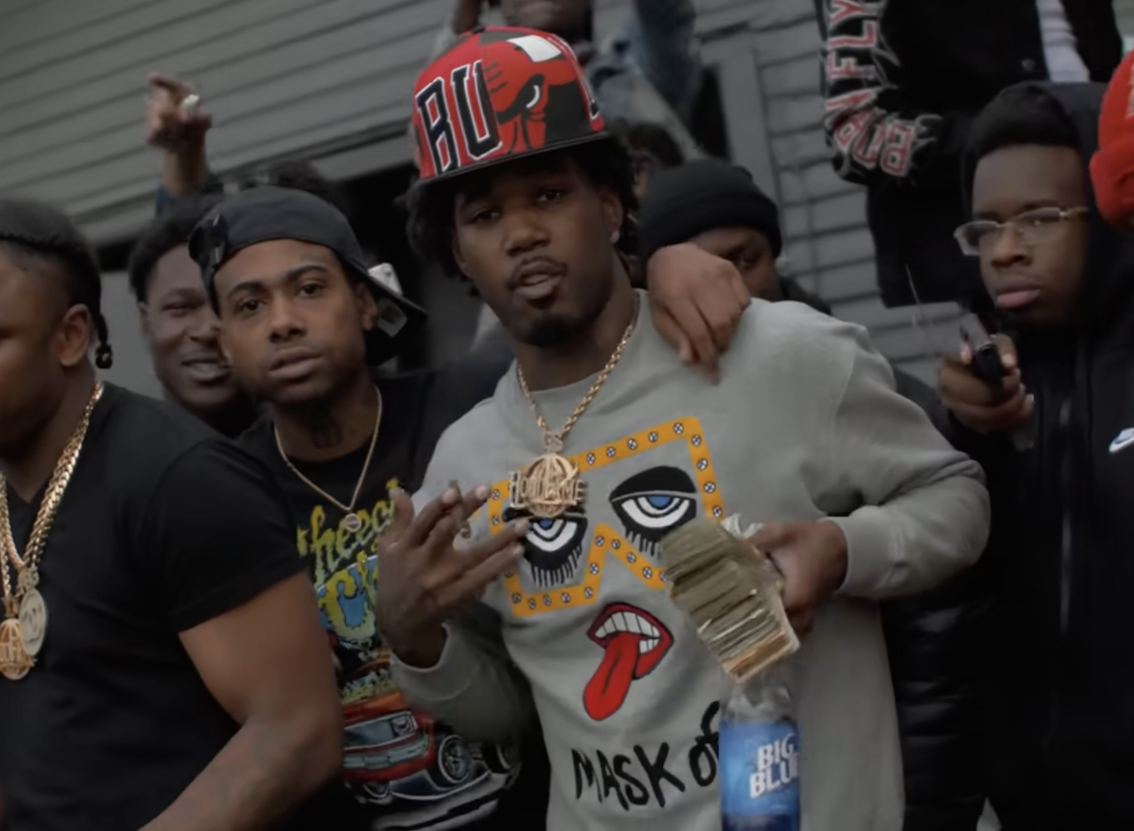 A group of men posing together, one wearing a Bulls cap and holding cash and a drink. They appear relaxed and confident.