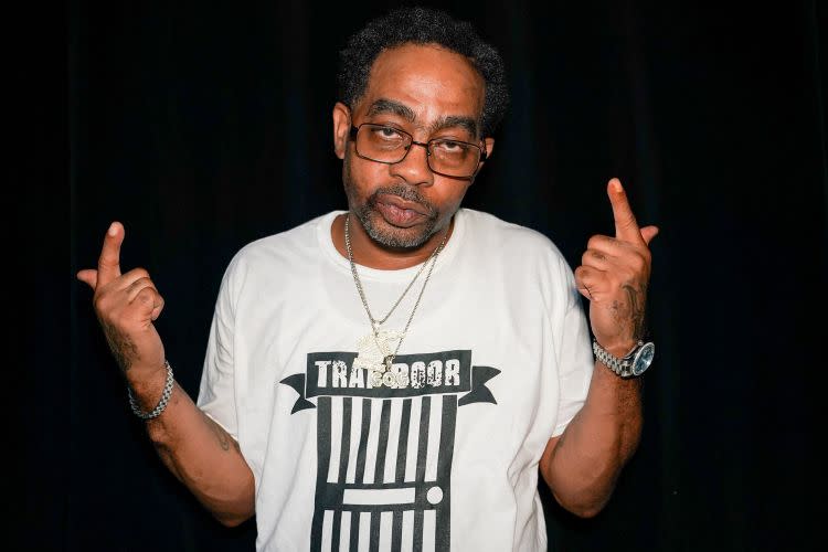 A man wearing glasses, a white T-shirt with 